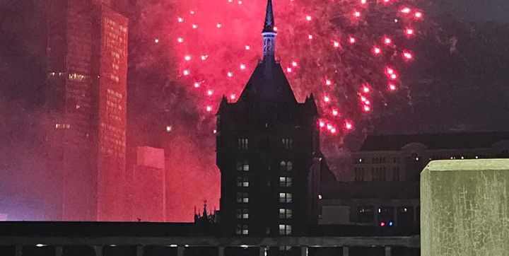Fireworks exploding in the background of an urban skyline. (it's Albany NY but you can't tell by looking at it)