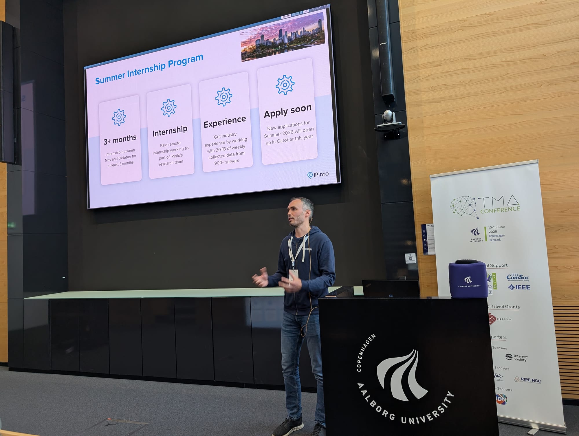 Head of Research Oliver Gasser standing on stage at TMA 2025 presenting a slide on IPinfo's summer internship program