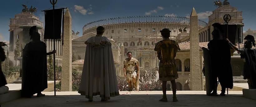 Roman gladiator approaching figures on a terrace overlooking a crowded colosseum, from a historical epic film scene.