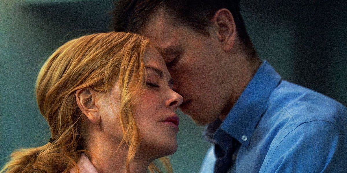 Two people in an intimate close-up, foreheads touching with eyes closed, woman with blonde hair and man in blue shirt.