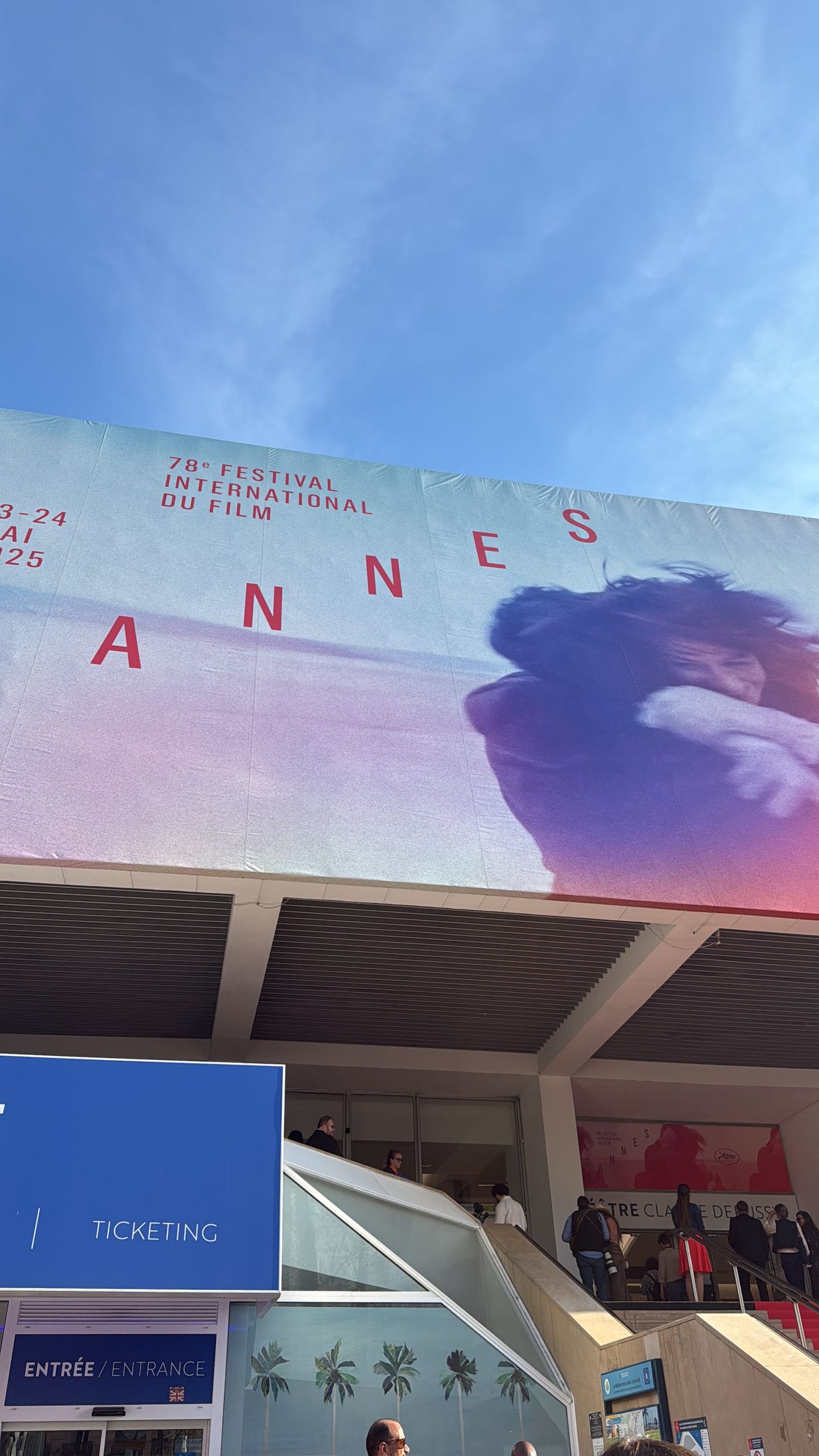 Large banner for 78th Cannes International Film Festival, May 13-24, 2025, on building facade with ticketing area below.