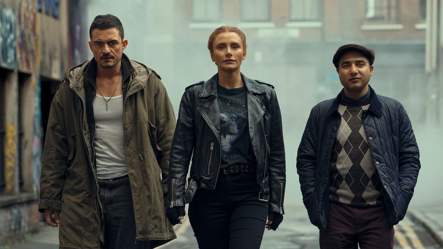 Three people walk toward the camera down a foggy urban alley with graffiti walls, wearing jackets in a cinematic style.
