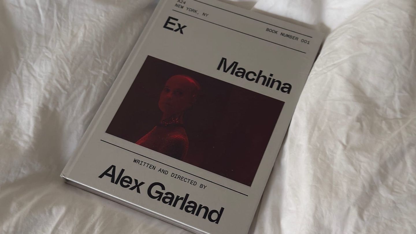 Book cover of "Ex Machina" by Alex Garland, published by A24, Book Number 001, with a red-tinted photo of a figure, on white bedsheets.