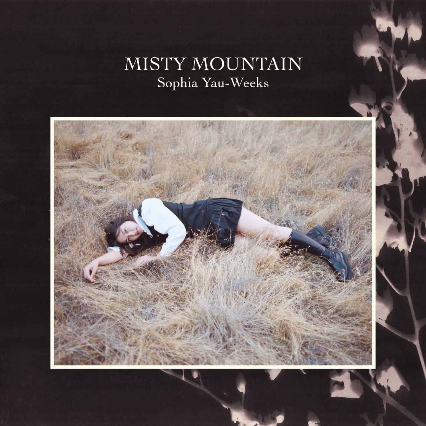 Album cover for "Misty Mountain" by Sophia Yau-Weeks, showing a woman lying in dry grass, wearing a white top and black skirt.