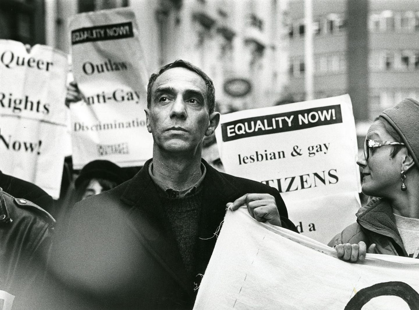 Black-and-white photo of demonstrators holding signs reading “EQUALITY NOW!” and calling for lesbian and gay rights.