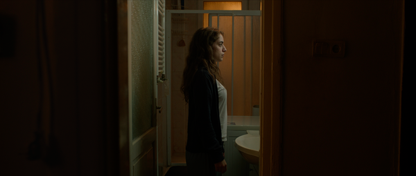Isolated in her bathroom, Deniz, the film's protagonist, looks into a mirror.