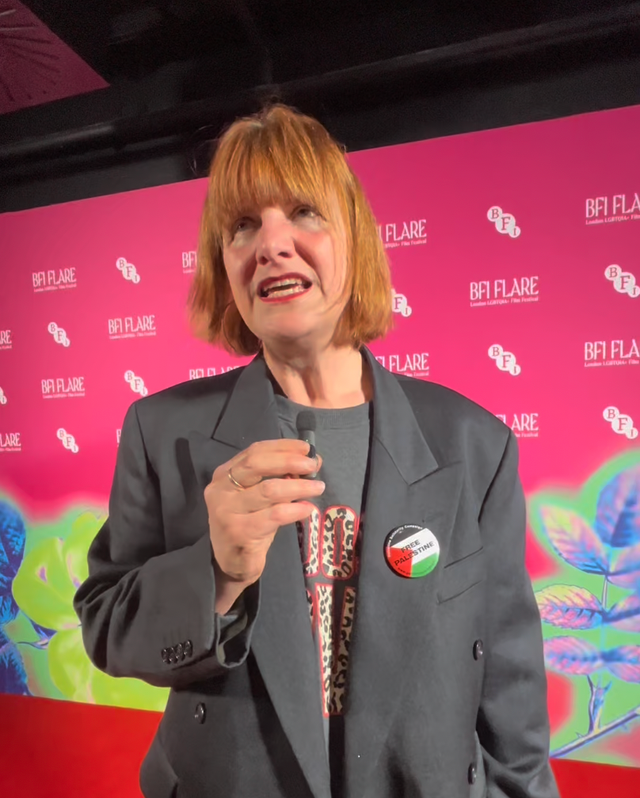 Woman with red bob hair in gray blazer speaking at BFI Flare film festival, wearing a "Free Palestine" pin badge.