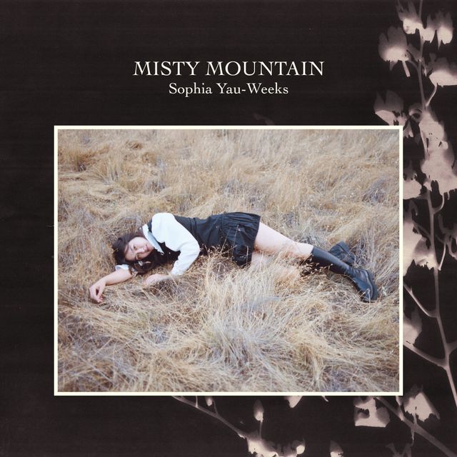 Album cover for "Misty Mountain" by Sophia Yau-Weeks, showing a woman lying in dry grass, wearing a white top and black skirt.