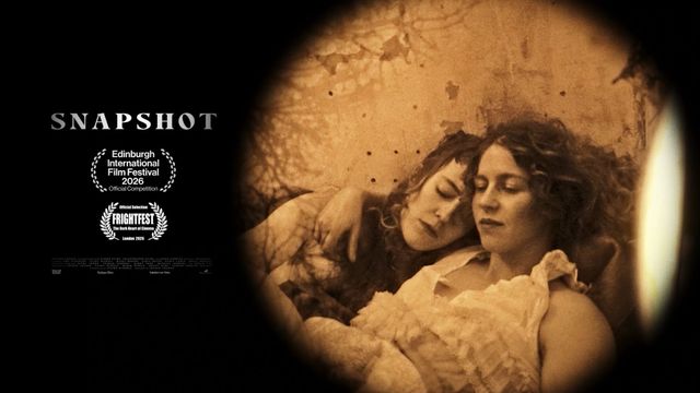 Two women in Victorian dress framed through a pinhole camera in Snapshot.