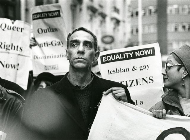 Black-and-white photo of demonstrators holding signs reading “EQUALITY NOW!” and calling for lesbian and gay rights.