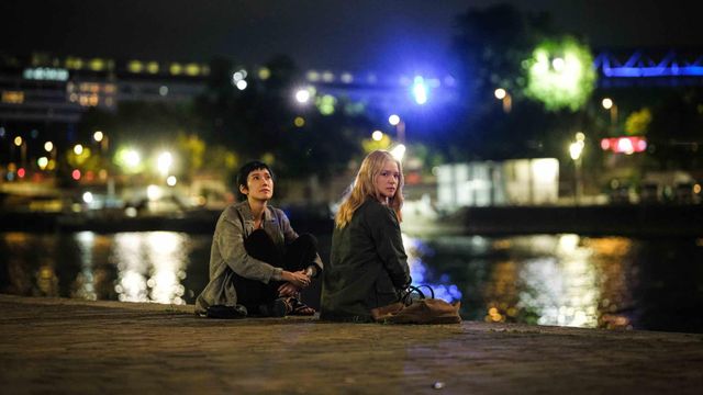 Tao Okamoto as Mari Morisaki and Virginie Efira as Marie-Lou Fontaine sit by a river at night in All of a Sudden.
