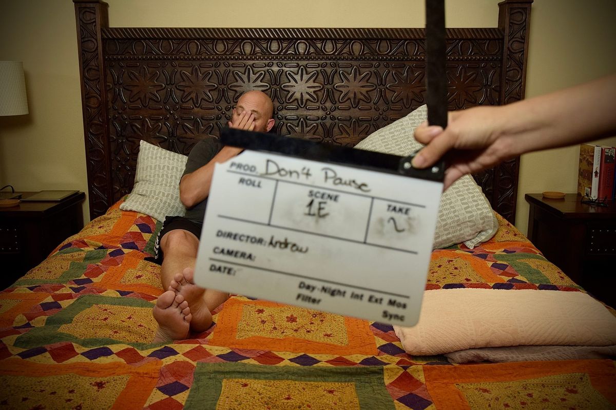 Man laying in bed, preparing for a video shoot
