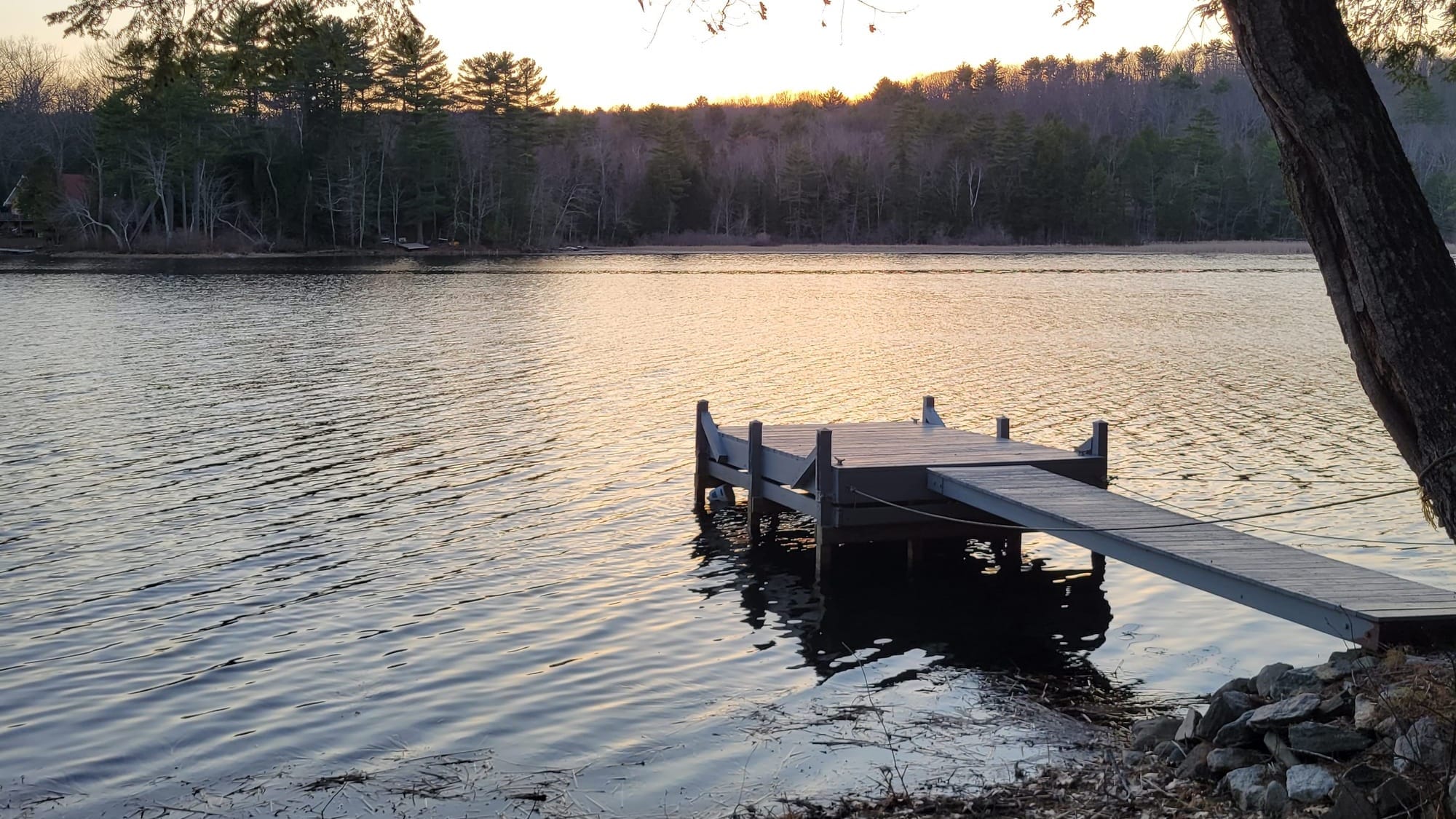 A serene dock stretching into a calm lake at sunrise, offering a tranquil space for quiet reflection.