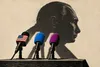 Politische Illustration: Drei Mikrofone mit US-Flagge, blauem und violettem Windschutz werfen gemeinsam einen Schatten in Form von Wladimir Putins Profil.