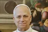 Papst Leo XIV. in weißer Soutane und mit weißer Kappe. Er lächelt leicht in die Kamera, im Hintergrund ist ein Gemälde zu sehen.