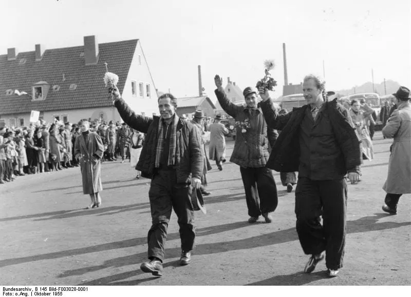 Heimkehrende deutsche Kriegsgefangene winken im Oktober 1955 im Lager Friedland mit Blumen.