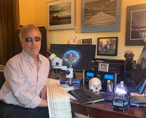Douglas Seiler sitzt in seinem Arbeitszimmer zwischen Mikroskop, Computern und technischen Geräten.
