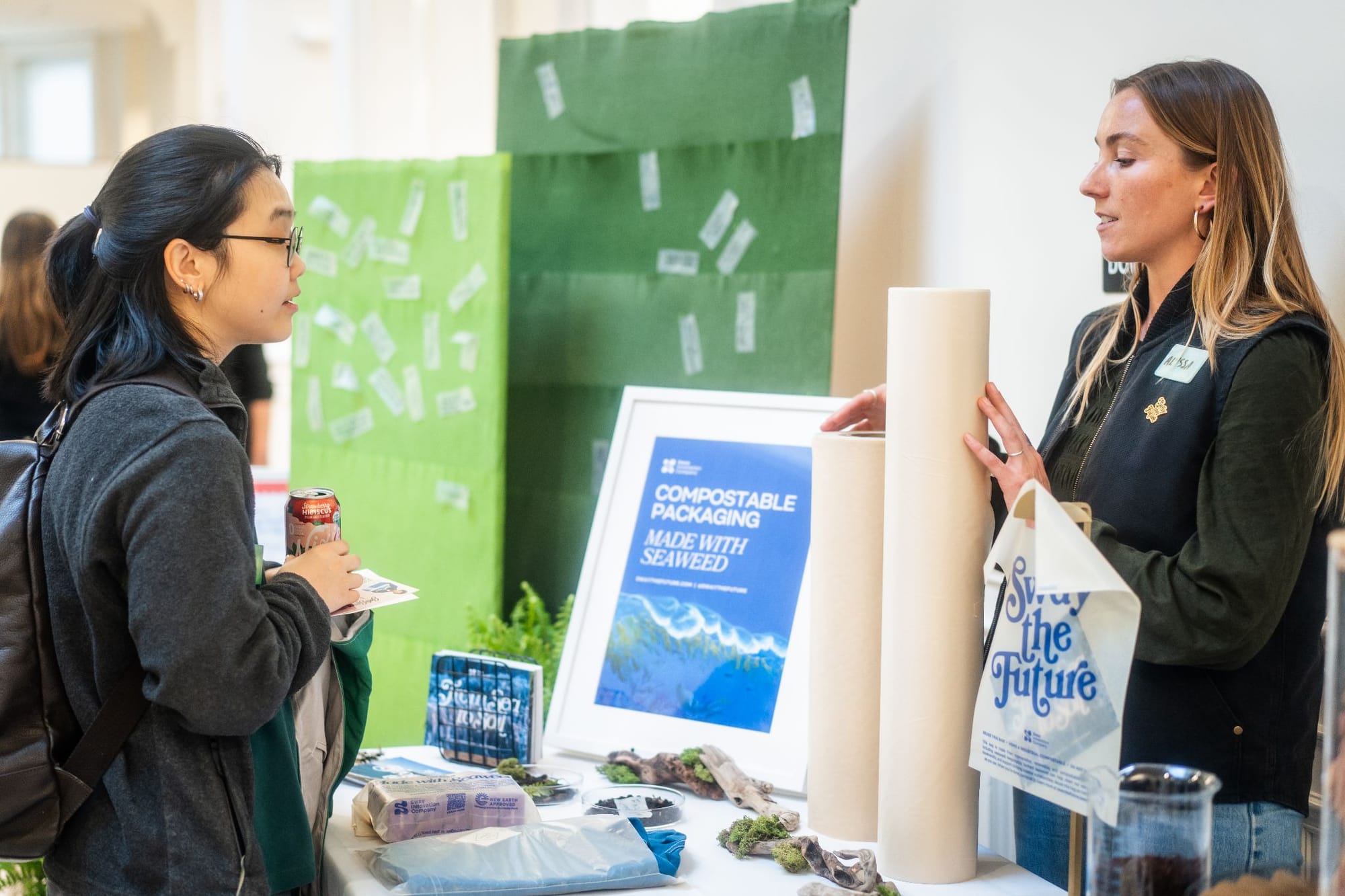 Two women at a booth displaying Sway's packaging products