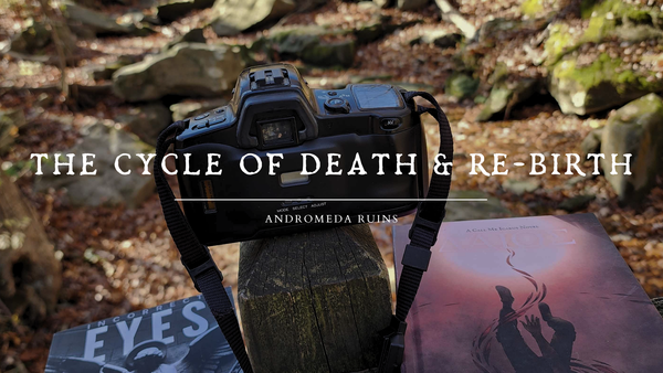 a photo of a film camera sitting on a wooden post with paperback copies of my books Incorrect Eyes and ΔΆΙΟΣ below them. The background of the image is Deer Lick Cave covered in fallen leaves