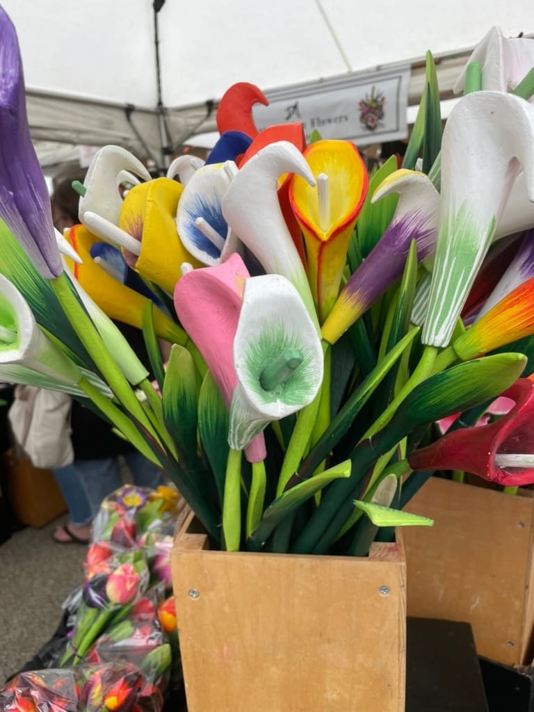 a bouquet of tulips carved out of wood and painted in yellow, orange, pink, white, and green. All have green stems