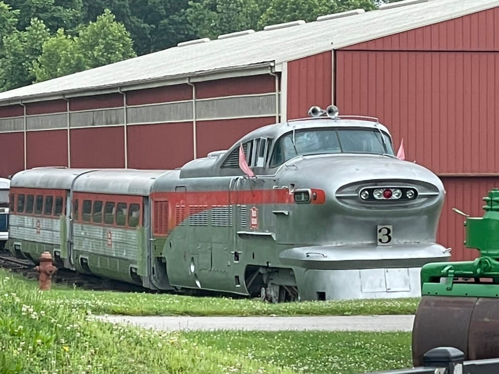 A silver train with a red streak. It has an odd shaped "jet nose" with an ovel on the front and silver horns on top.
