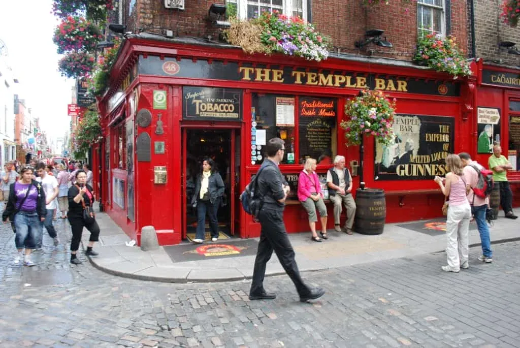 Tourist walking around Dublin, Ireland in front of Temple bar, a popular bar with red color on the exterior. 