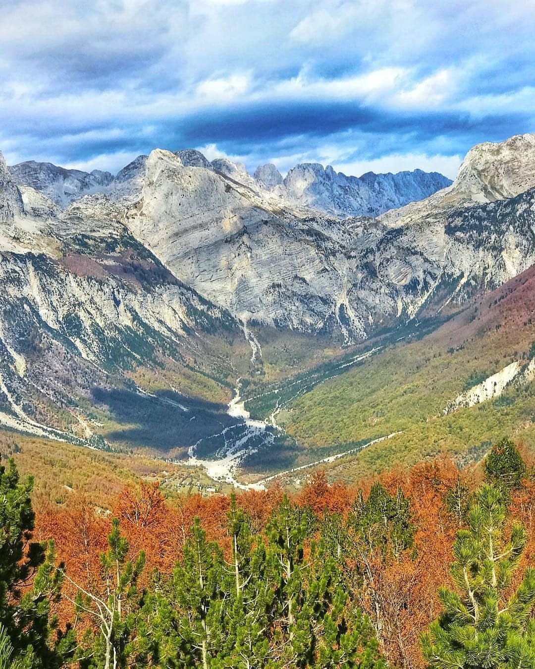 Theth Valley in Theth National Park, Albania, with rugged peaks of the Accursed Mountains and forested slopes in autumn colors.