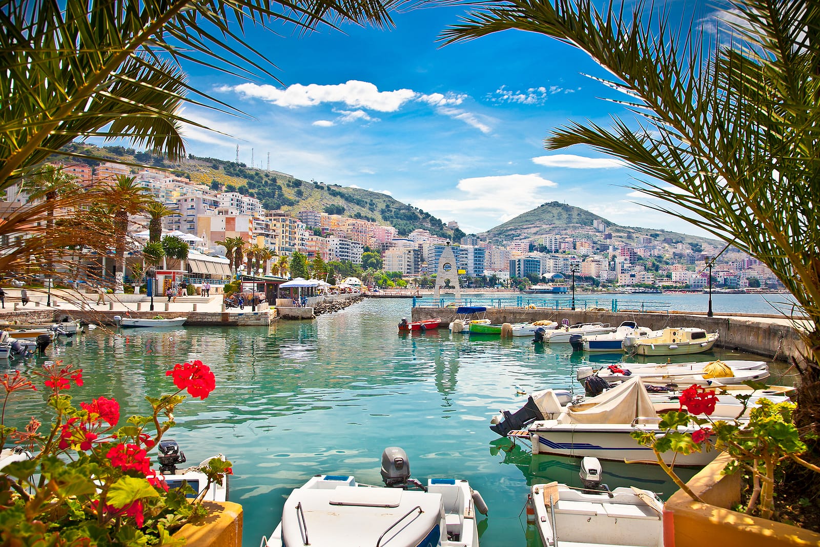 boats at a dock in a seaside village with pretty flowers and tropical looking trees in Saranda.