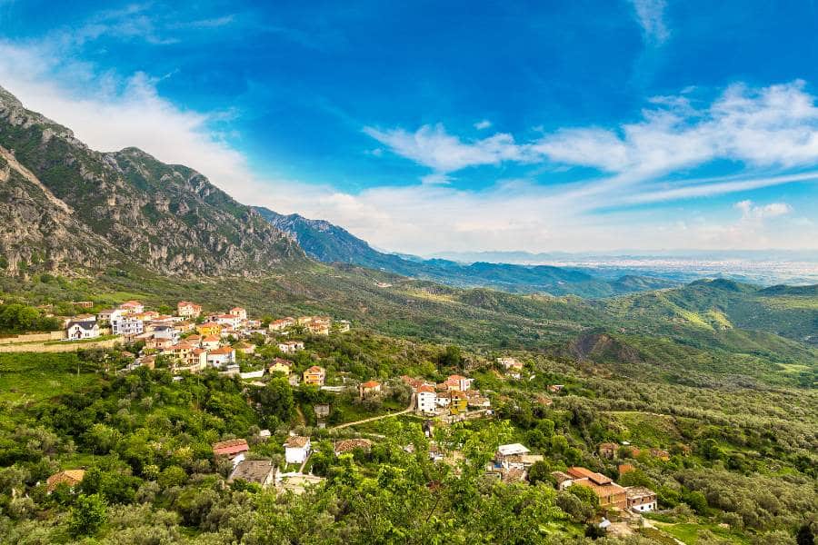 Kruja homes on the hillside surrounded by mountains in lush green forests.