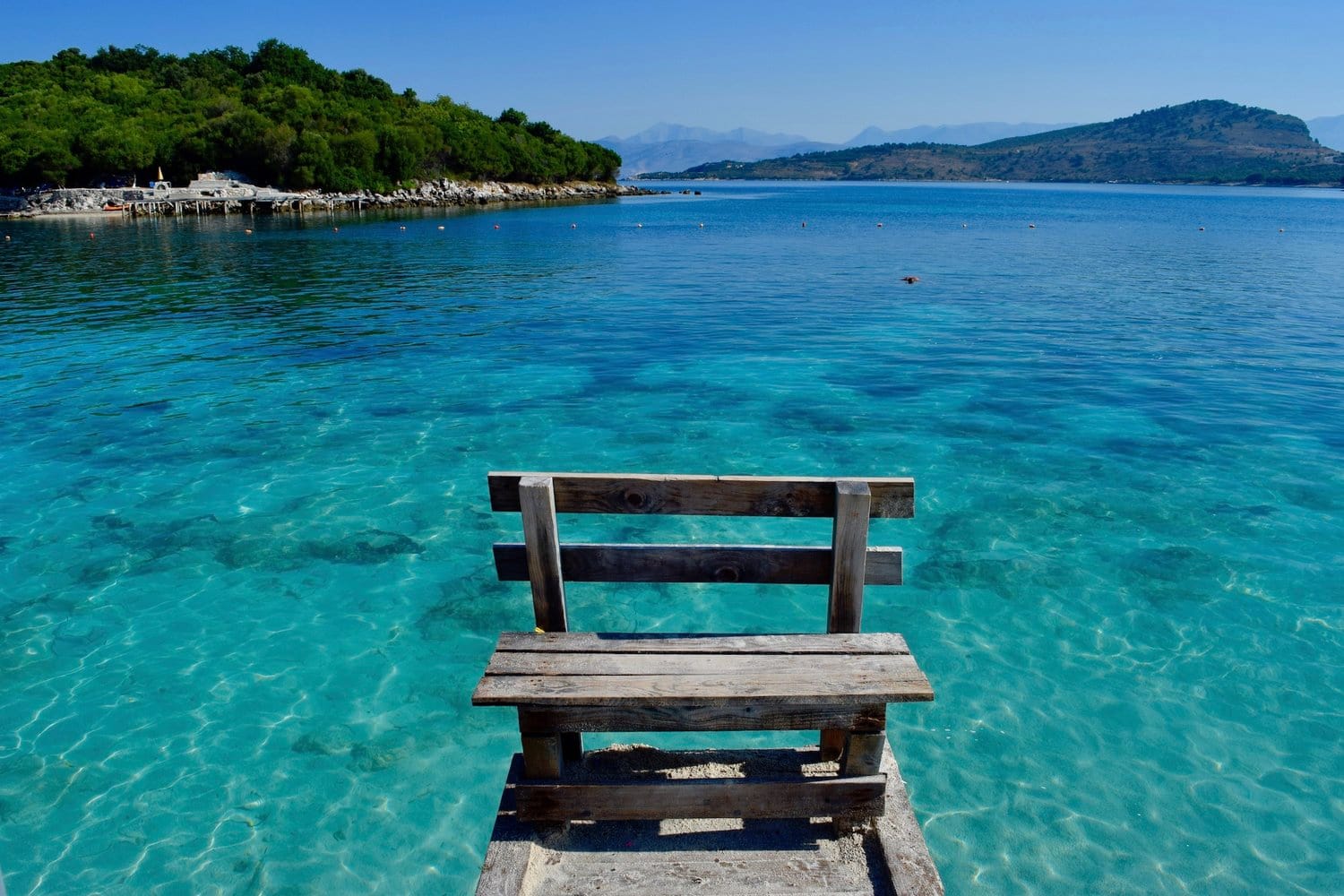 beautiful clear water with a wooden dock extending out on the water 