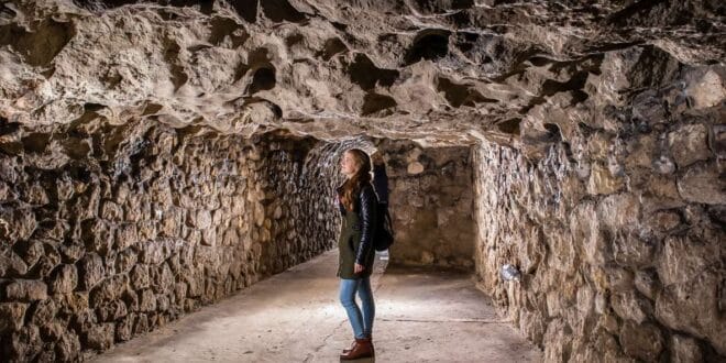 A person walking in the underground rock tunnels of Buda Castle. 