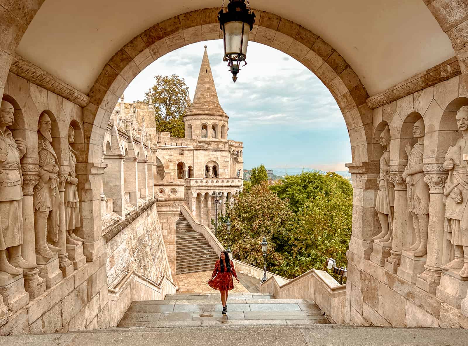 A woman in a red dress walking up the stairs of Fisherman’s Bastion in Budapest.