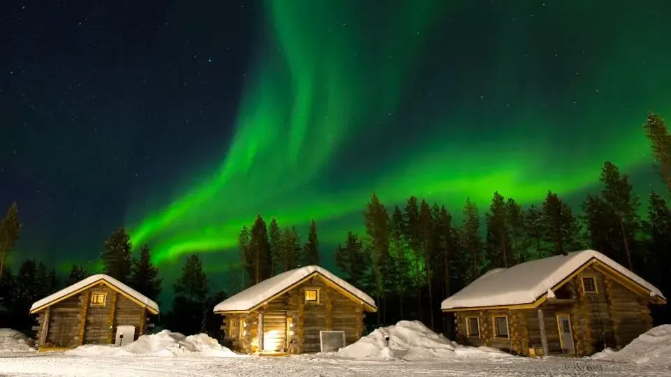 Northern Lights over snow covered roofs in Lapland.