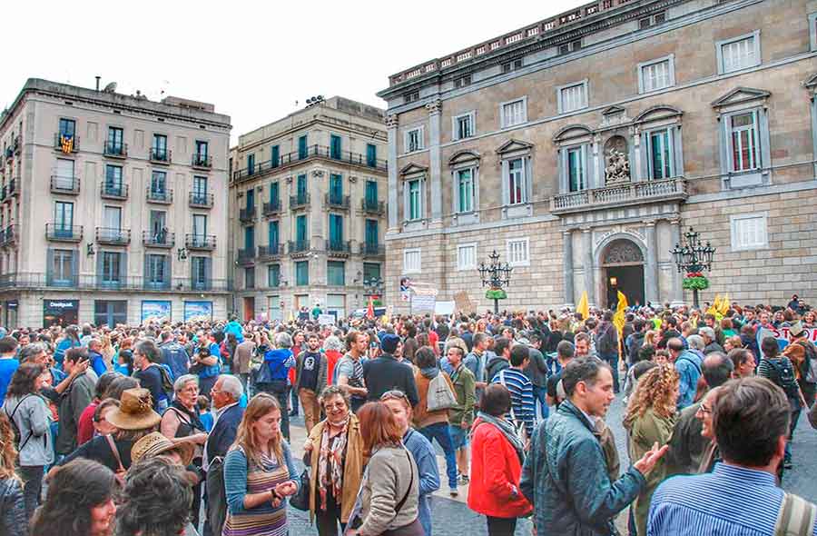 Lot's of people standing around socializing at Plaça Sant Jaume.