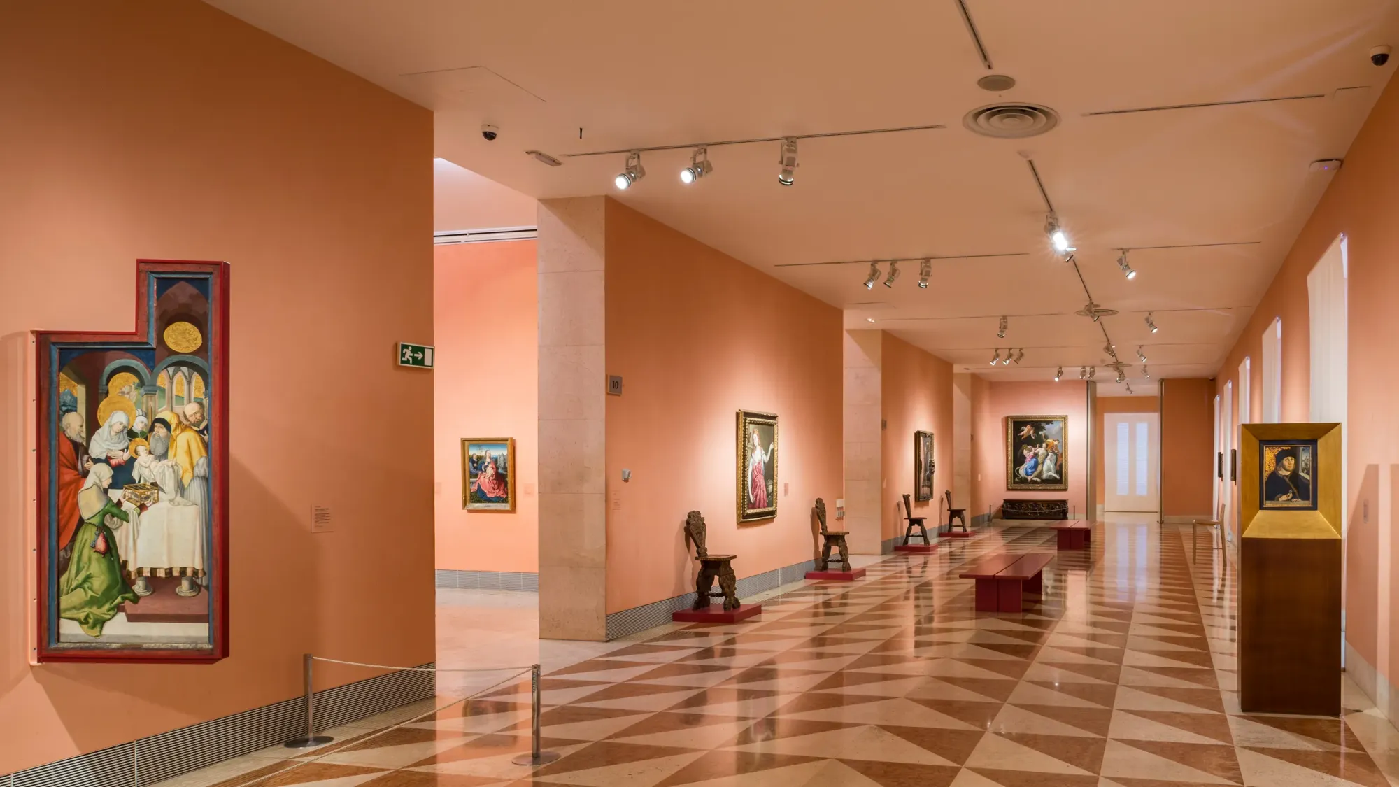 Thyssen-Bornemisza Museum has pink walls and ceiling with checked pink and red flooring and art work on he walls.
