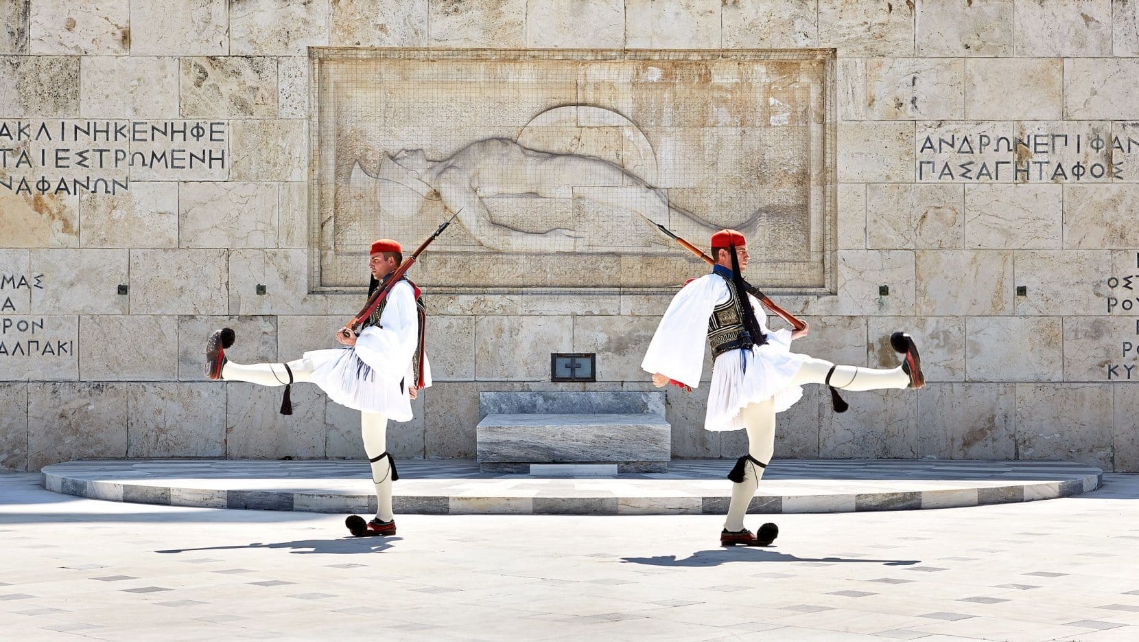 Two soldiers holding guns doing high steps at the changing of the Guard in Athens. 