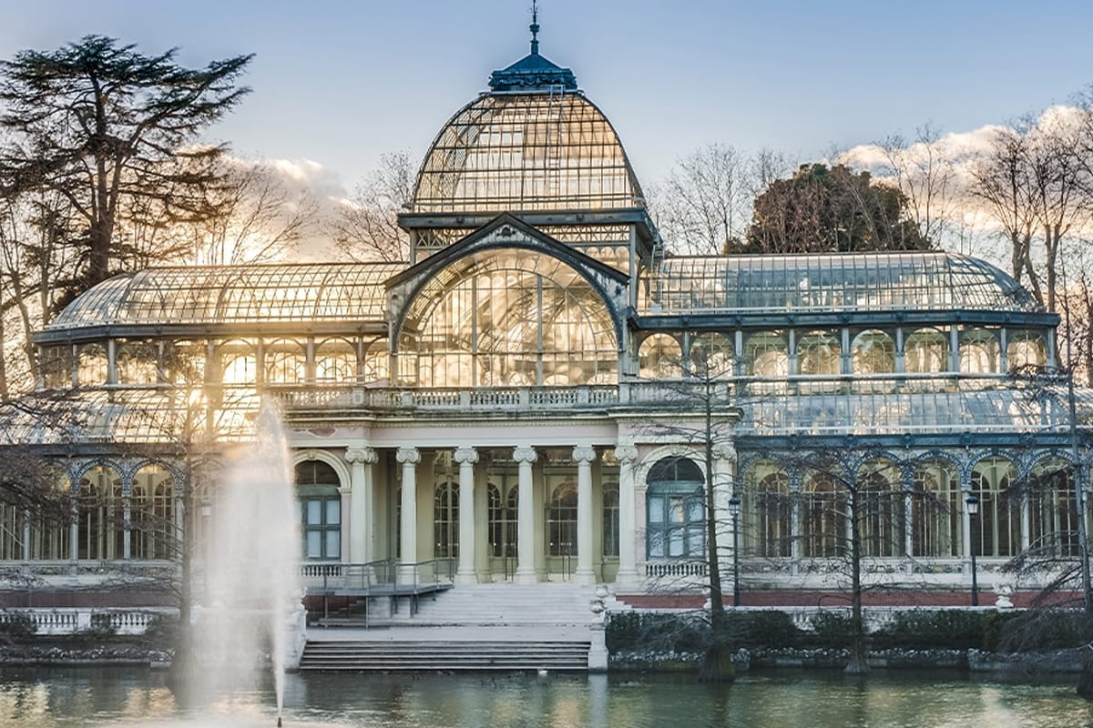 A long building that appears to be a type of greenhouse with a glass roof and walls at Retiro Park in Madrid.