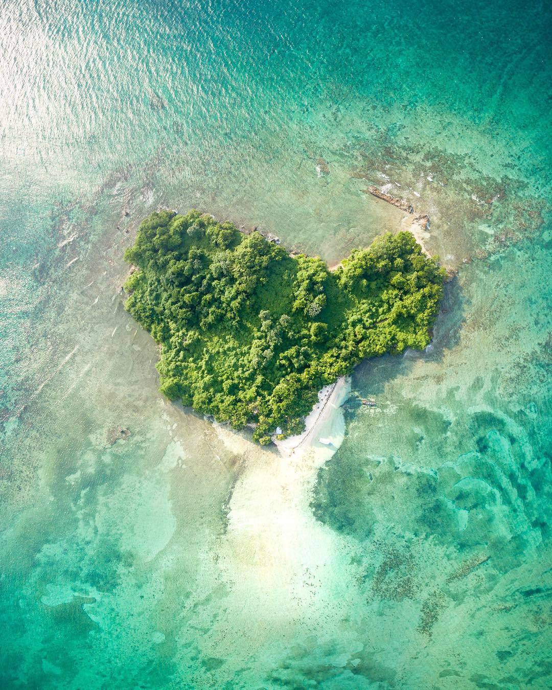 Ariel view of a beautiful tiny island with white sand and a patch of trees surrounded by the clearest waters at Booby Cay Island near Negril.