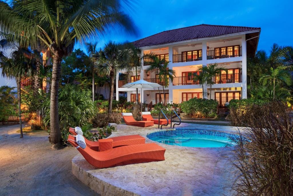 Three story resort with a hot tub sitting beside palm trees at Couples Swept Away Resort in Negril, Jamaica.