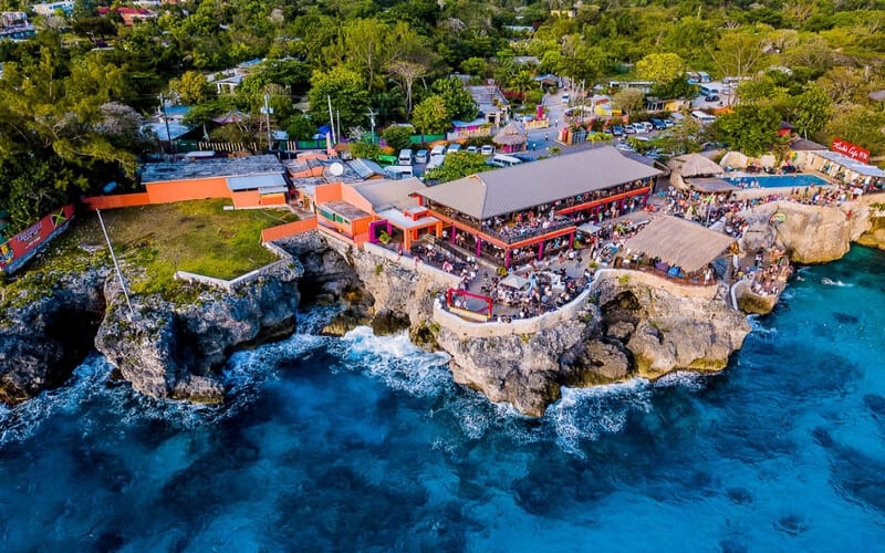 Ariel view of Rick’s Café Negril on the cliffs overlooking beautiful clear blue waters.
