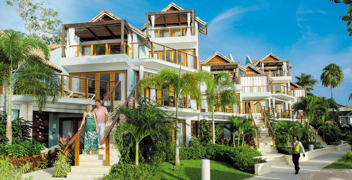 Waiter walking on the sidewalk with drinks outside of Sandals Beach resort Negril, Jamaica.