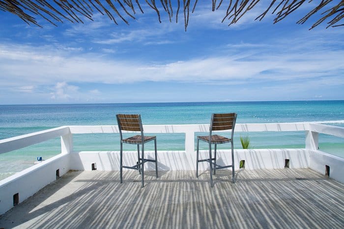 two chairs sitting on a wooden patio on the ocean front at White Sands Negril resort.