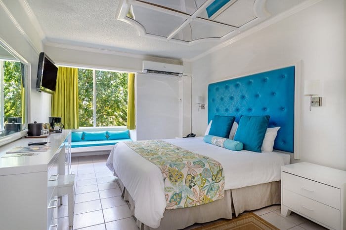 Guide room with white interior and a blue headboard at Hedonism II resort in Negril, Jamaica.