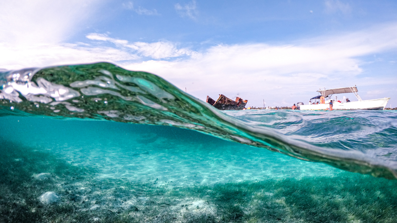 View underwater in Cancun with a boat shown on top of the water.