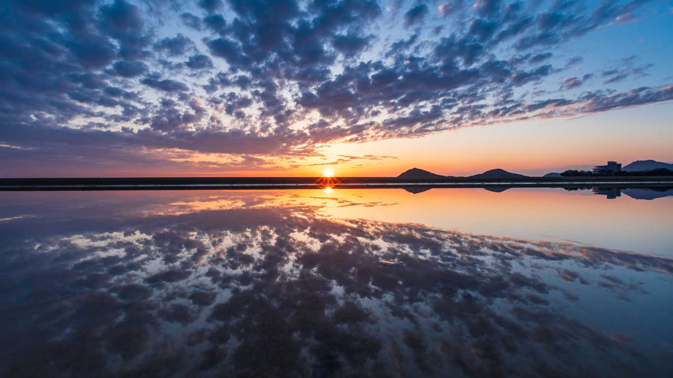 The sunset is reflecting off the water at a beautiful beach in Japan. 