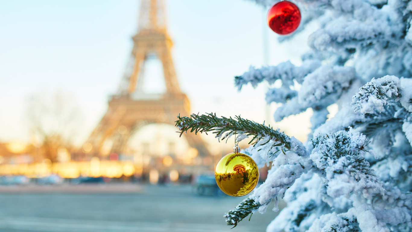 view of the Eiffel tower in the distance with Christmas tree with snow and ornaments showing how beautiful Paris is in the winter time