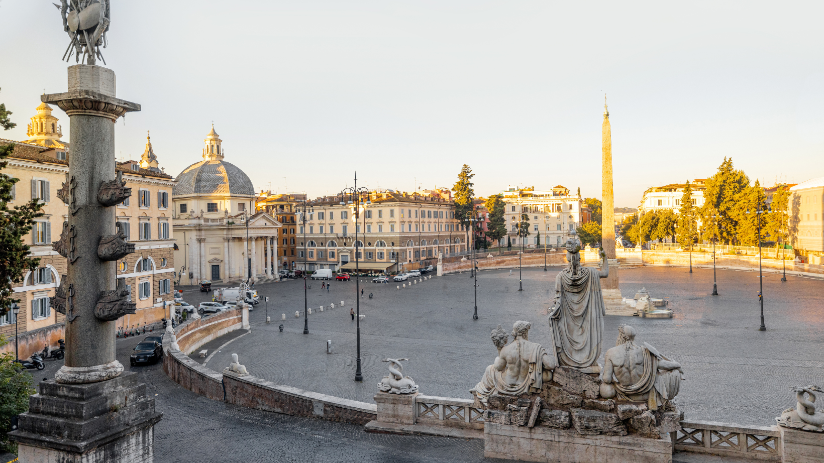 View a statue of 3 people at Piazza del Popolo in Rome