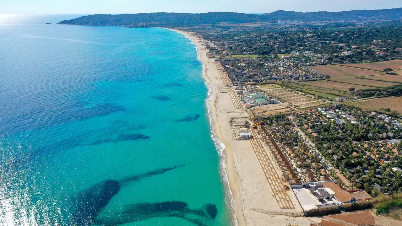 Ariel view of a long strait beach with clear blue waters. 