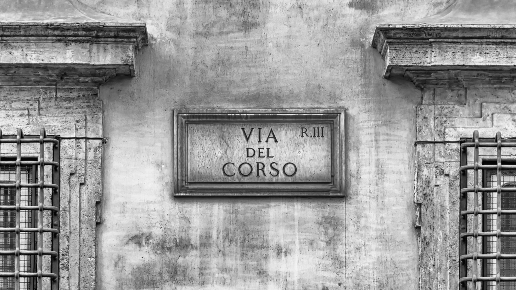 A Sign that says Via del Corso  on the side of a building.