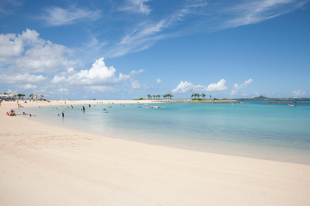 People are enjoying a white sand beach with clear ocean waters.